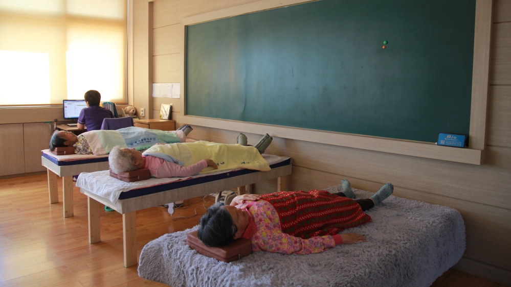 Elderly women lie down for a physiotherapy session at the Yaksu ‘Granny School’; the building was converted into a daycare centre for the elderly after the primary school closed in 2016