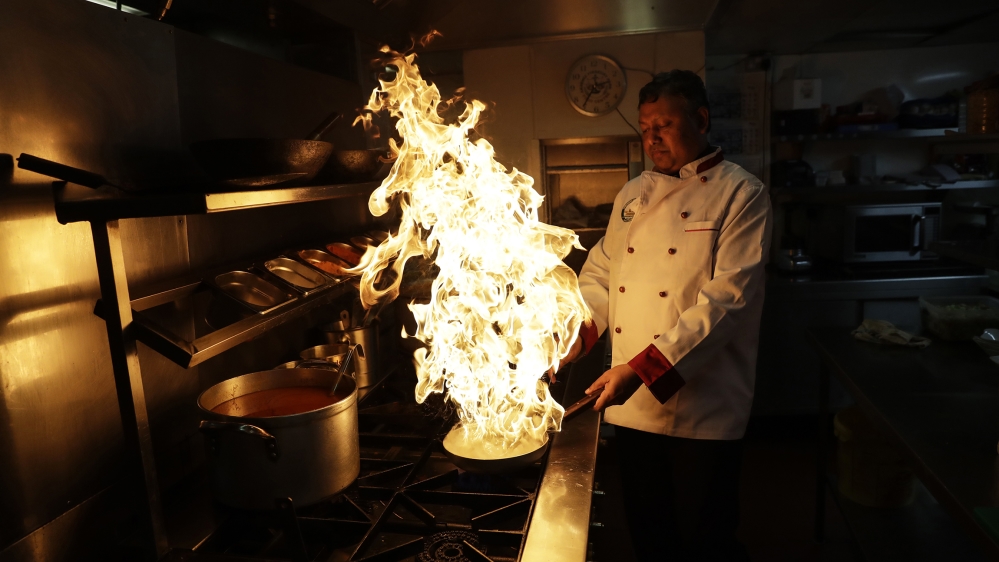 Chef Mohammed- Faizul Haque uses lemon juice to make flames as he demonstrates how to give a smokey flavour to dishes such as Kuchi Chilli Chicken at the Taste of India curry restaurant in London, Thursday, March 9, 2017