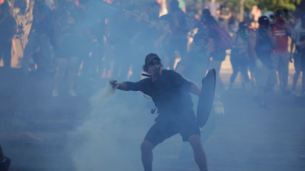 A protester throws back a canister of tear gas during a protest against Chile’s government in Santiago, Chile