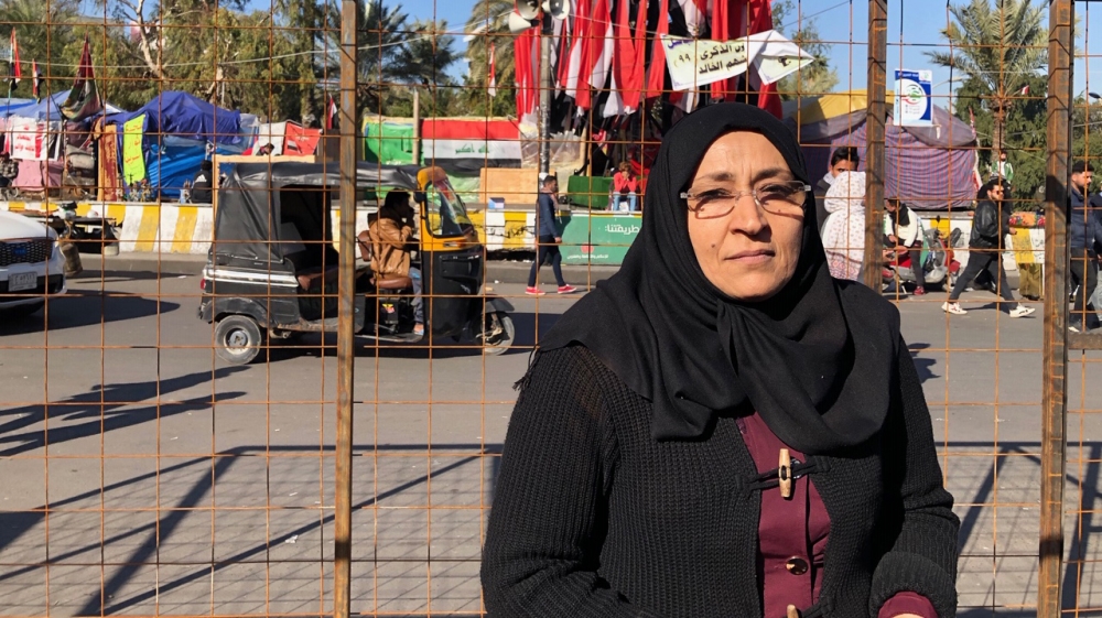 Umm Aqeel stands under the metal structure of her new tent after security forces burned her first one to the ground