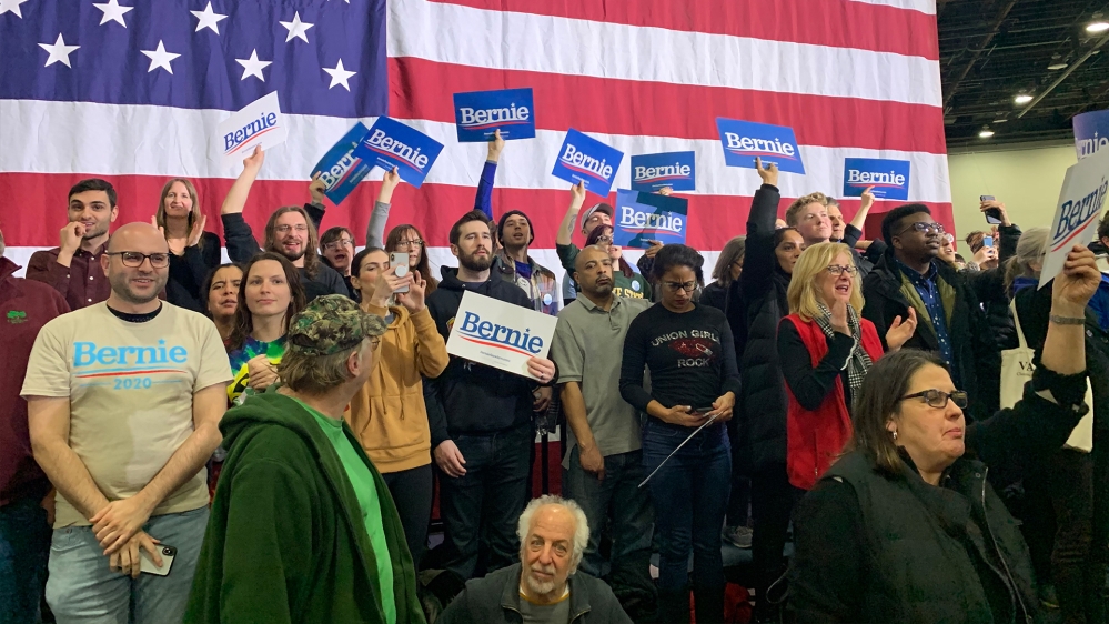 Bernie Sanders fans stand before a draped US flag at his rally in downtown Detroit on March 6, 2020
